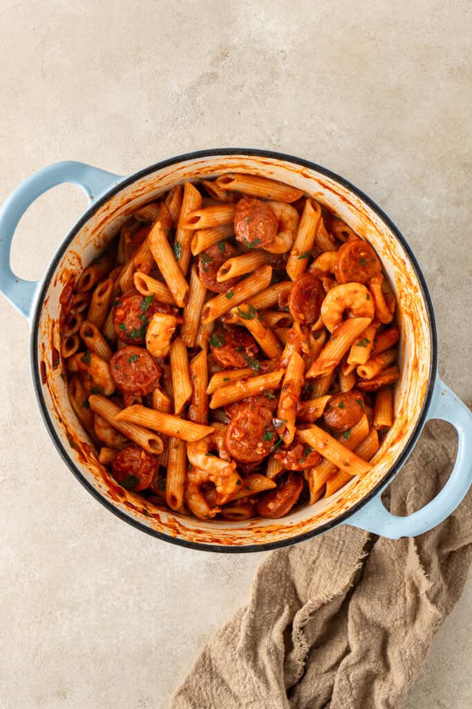 The cooked pasta added into the pot with the sauce.
