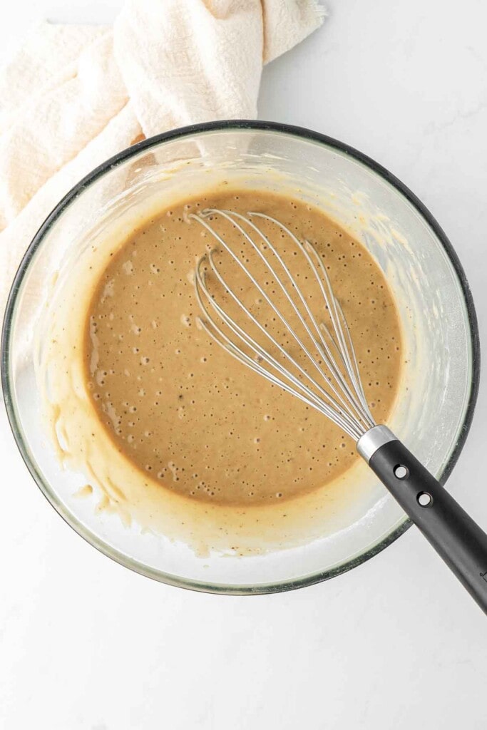 Cake batter in a bowl with a whisk.