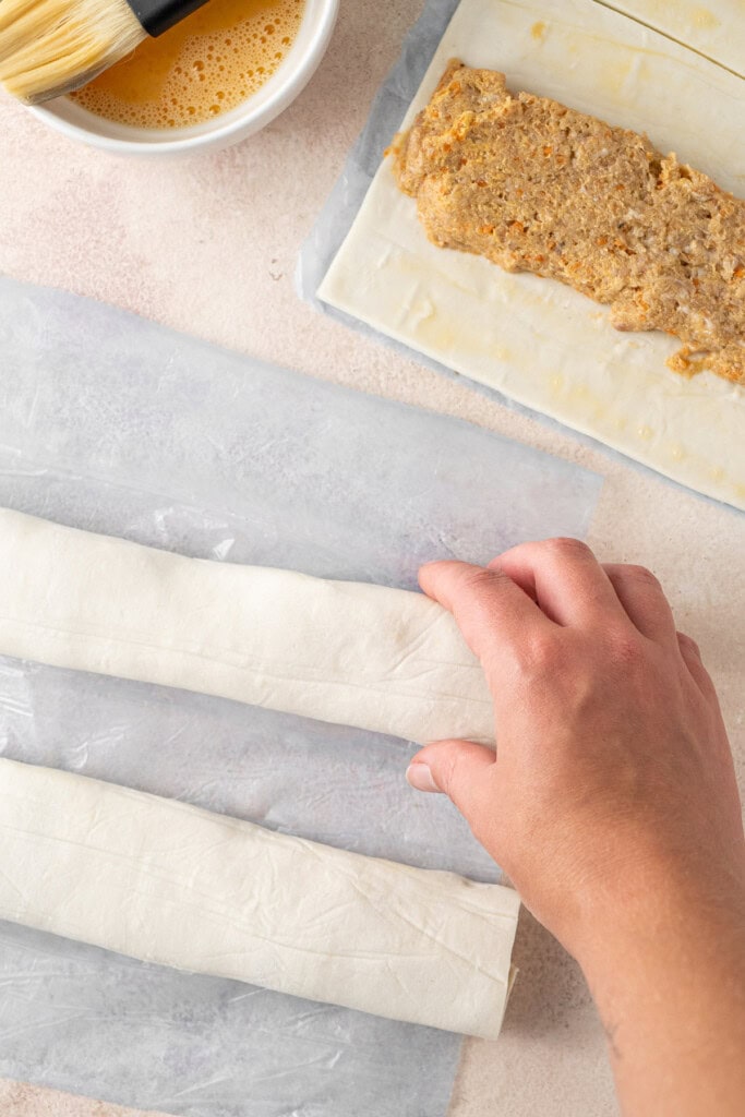 Rolling the pastry over the sausage filling.
