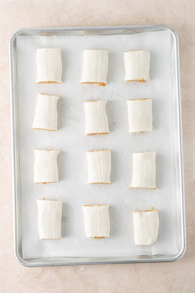 The cut sausage rolls on the baking tray.