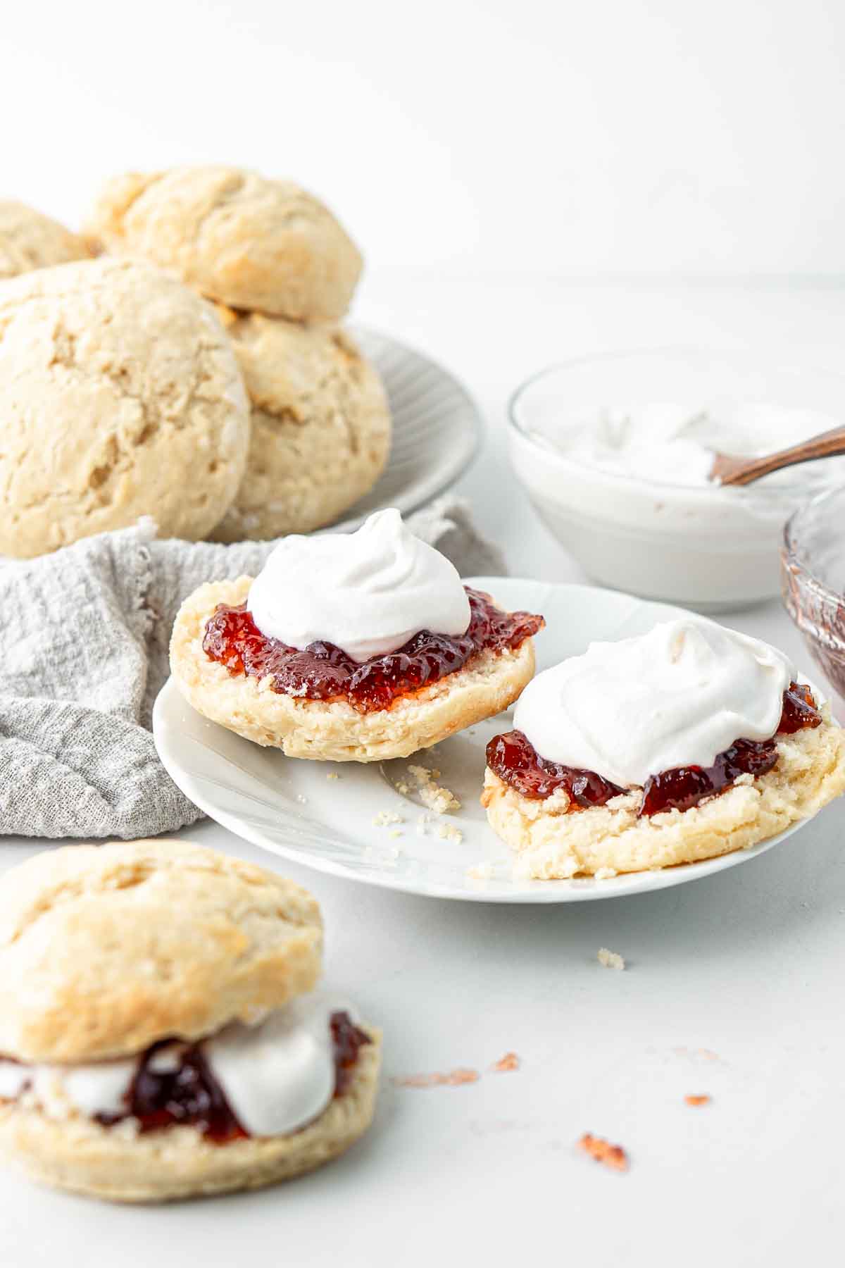 Scones with jam and cream on a white plate.