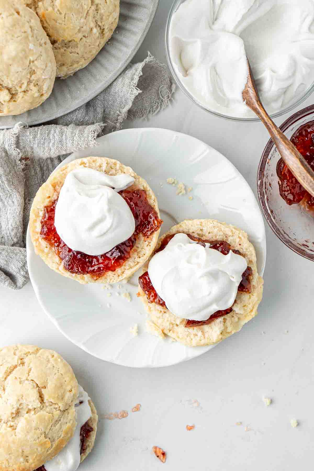 Scone that has been split and topped with jam and whipped coconut cream.