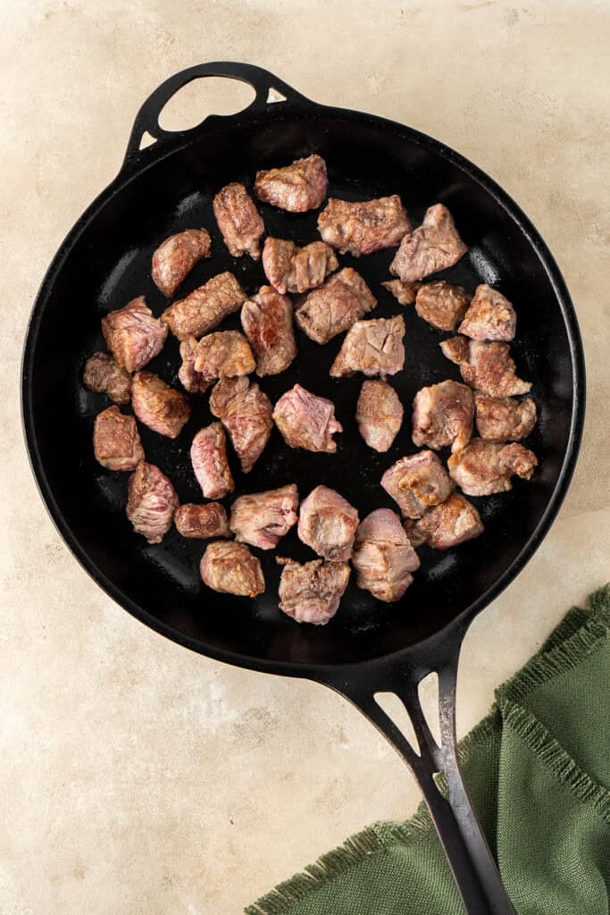 Browning the beef in a frying pan.