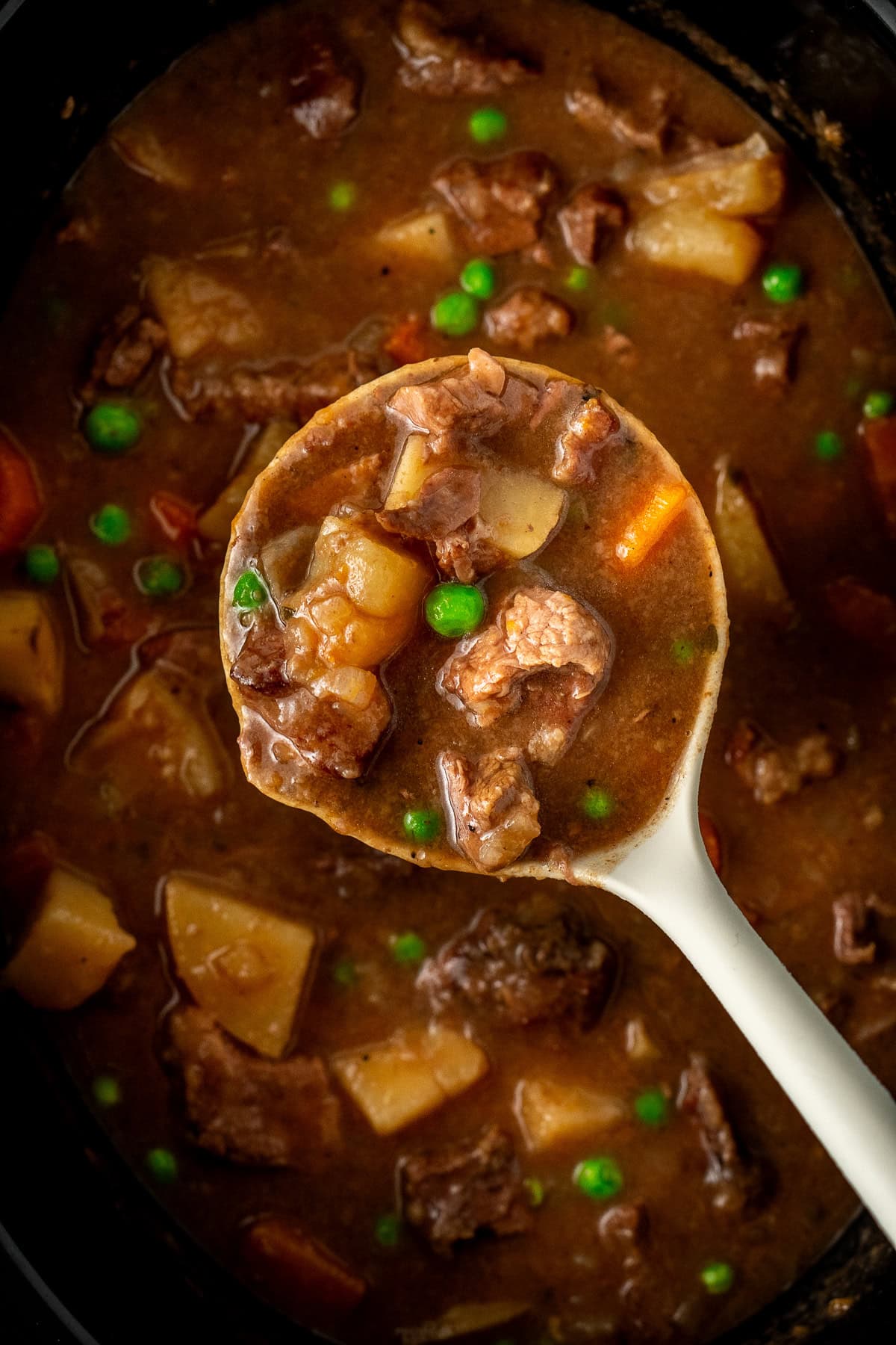 A ladle showing the cooked stew in the slow cooker.