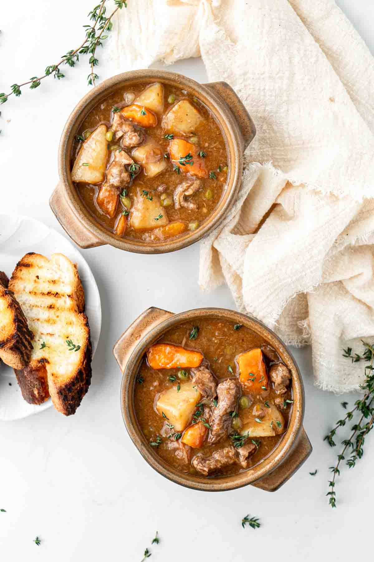 Beef stew served up in brown bowls with toasted bread.