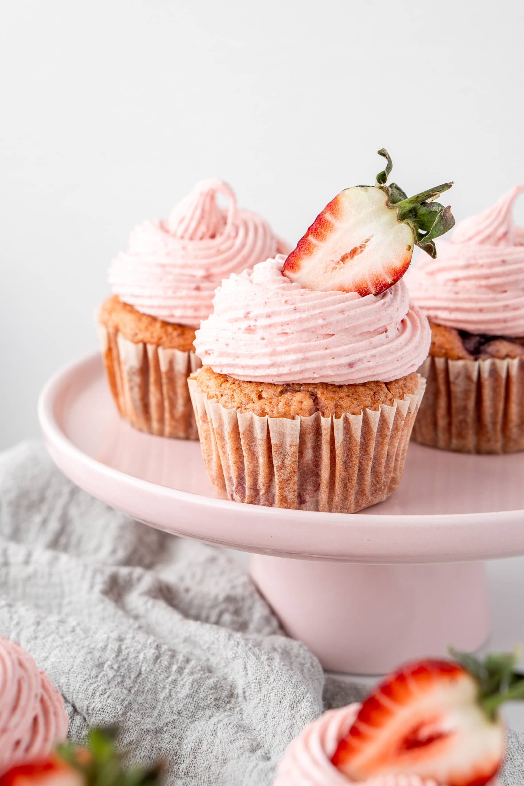 Close up of vegan strawberry cupcakes on a pink cake stand.