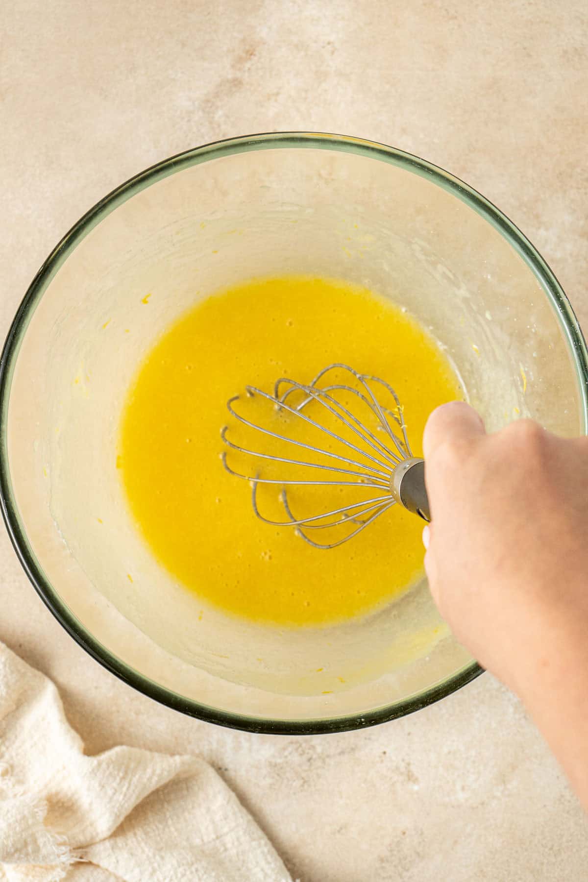 Whisking together the wet ingredients in a glass bowl.