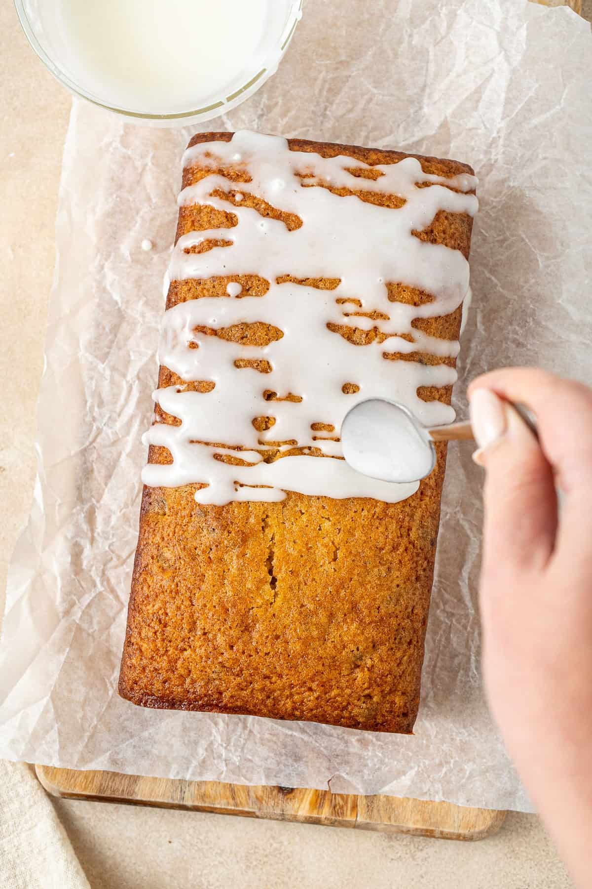 Drizzling the lemon glaze over the cake.