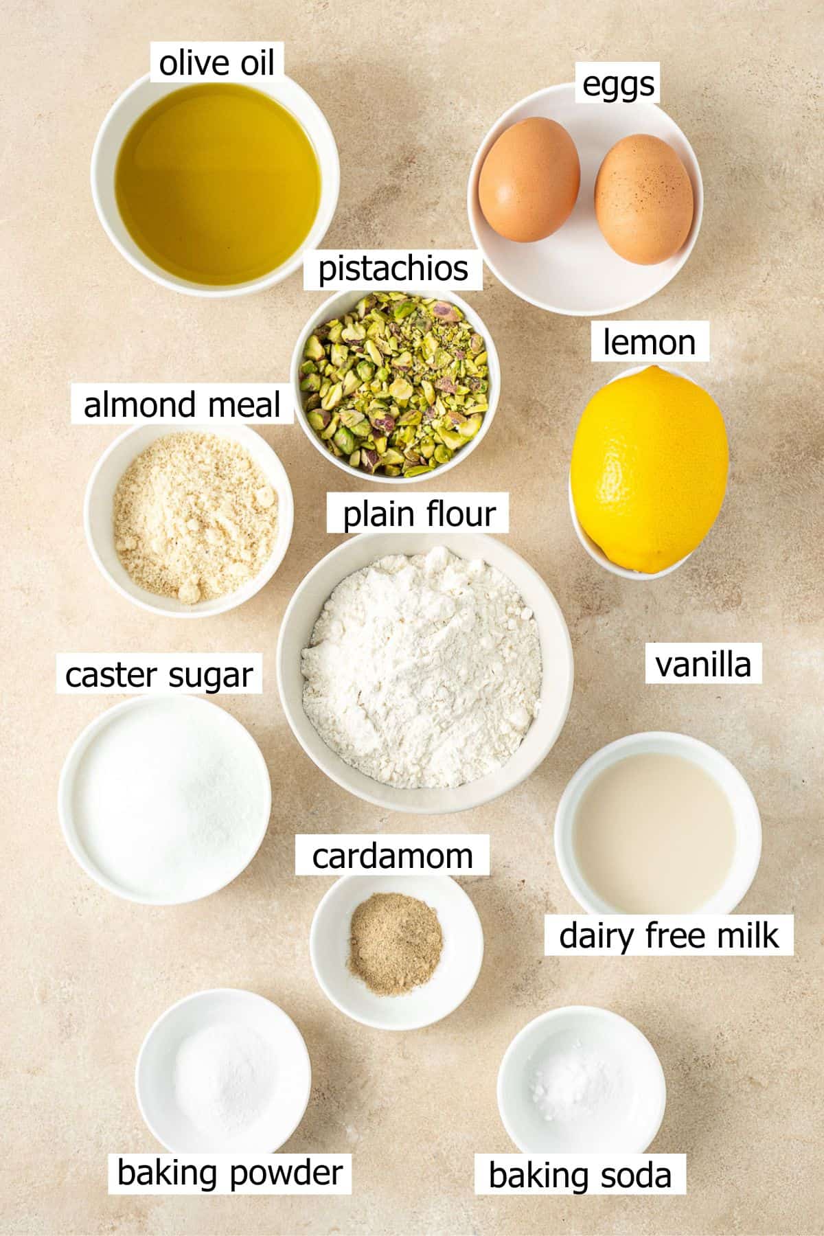 All ingredients needed to make a lemon pistachio loaf cake laid out in small bowls.