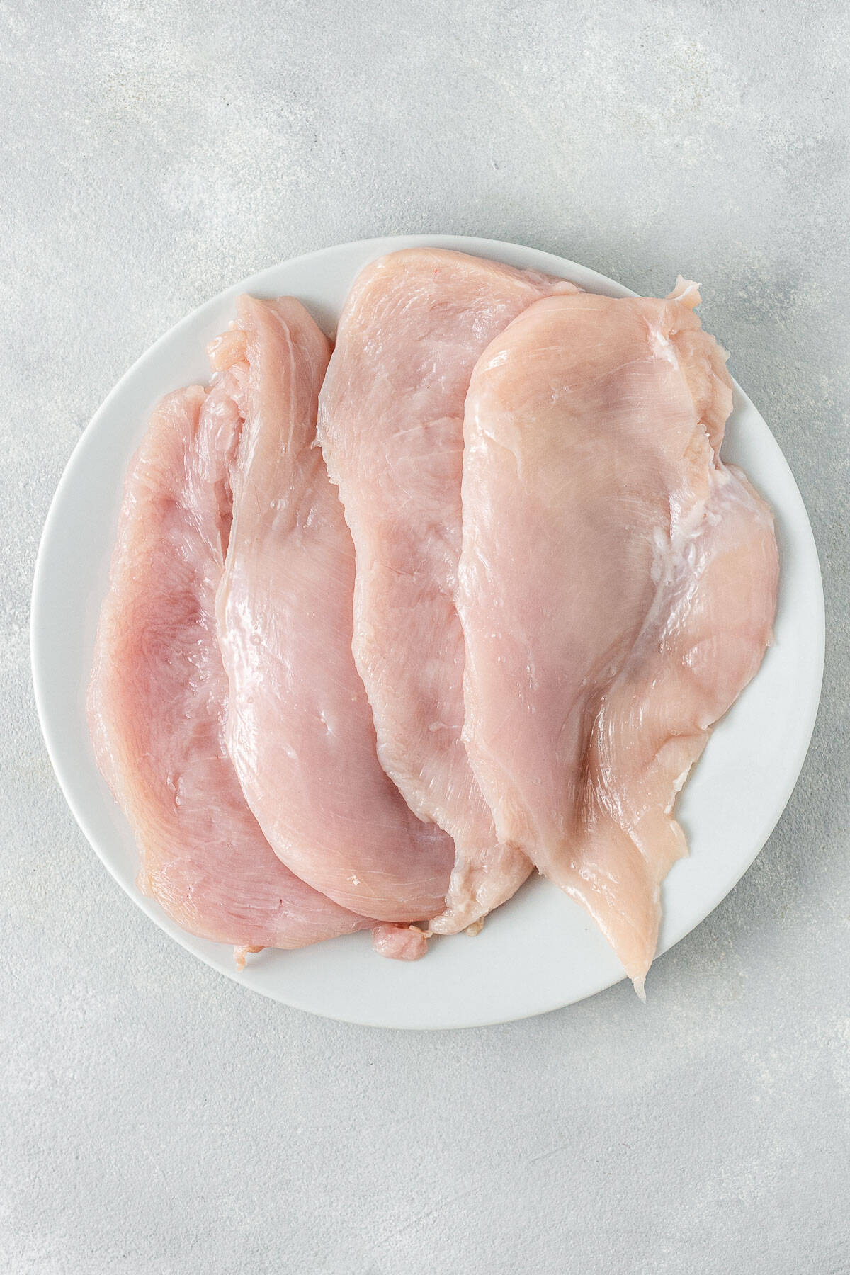 The raw chicken breasts cut on a plate.