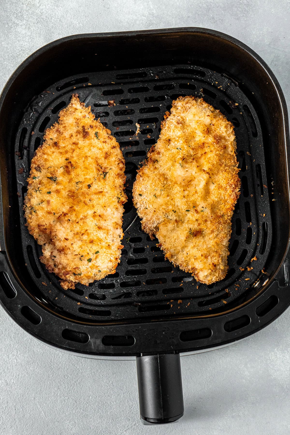 The cooked schnitzels in the air fryer basket.