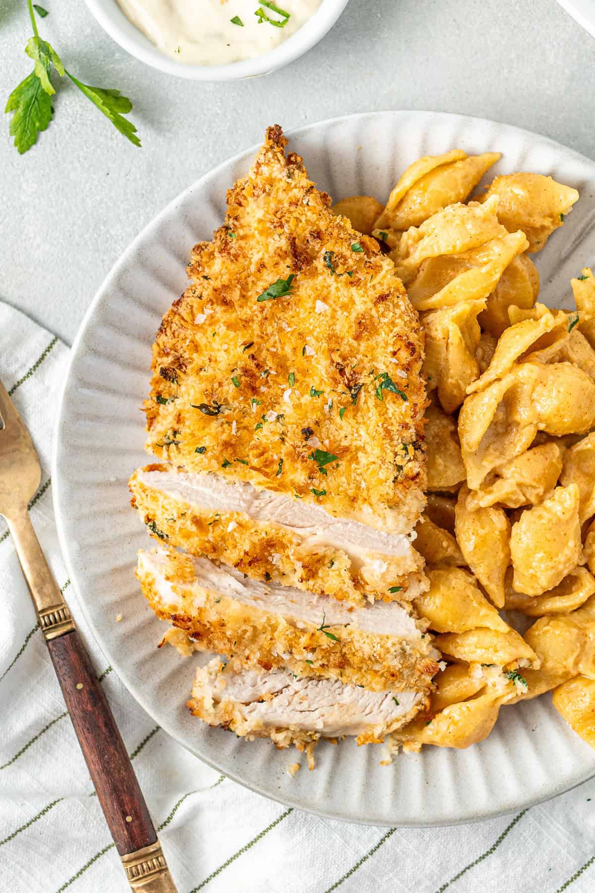 A chicken schnitzel served on a plate with dairy free mac and cheese.