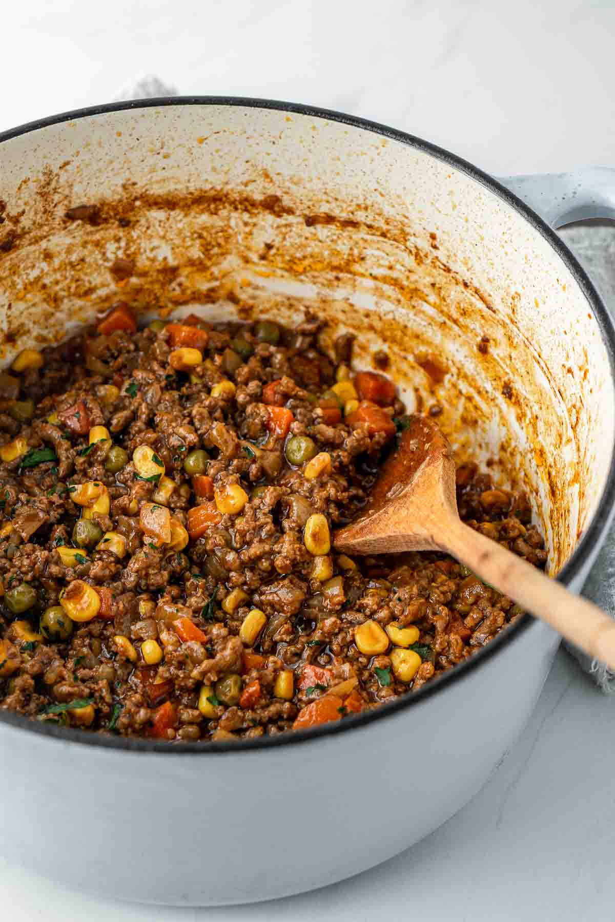 Savoury mince in a large pot with a wooden spoon.