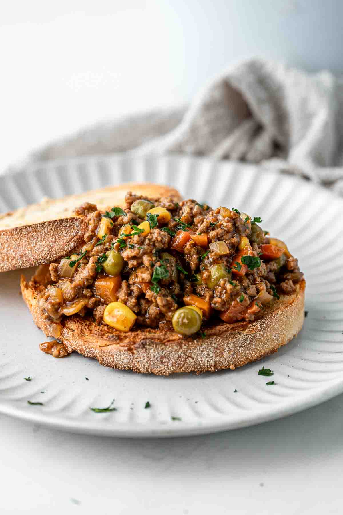 Savoury mince on toast with parsley on a white plate.