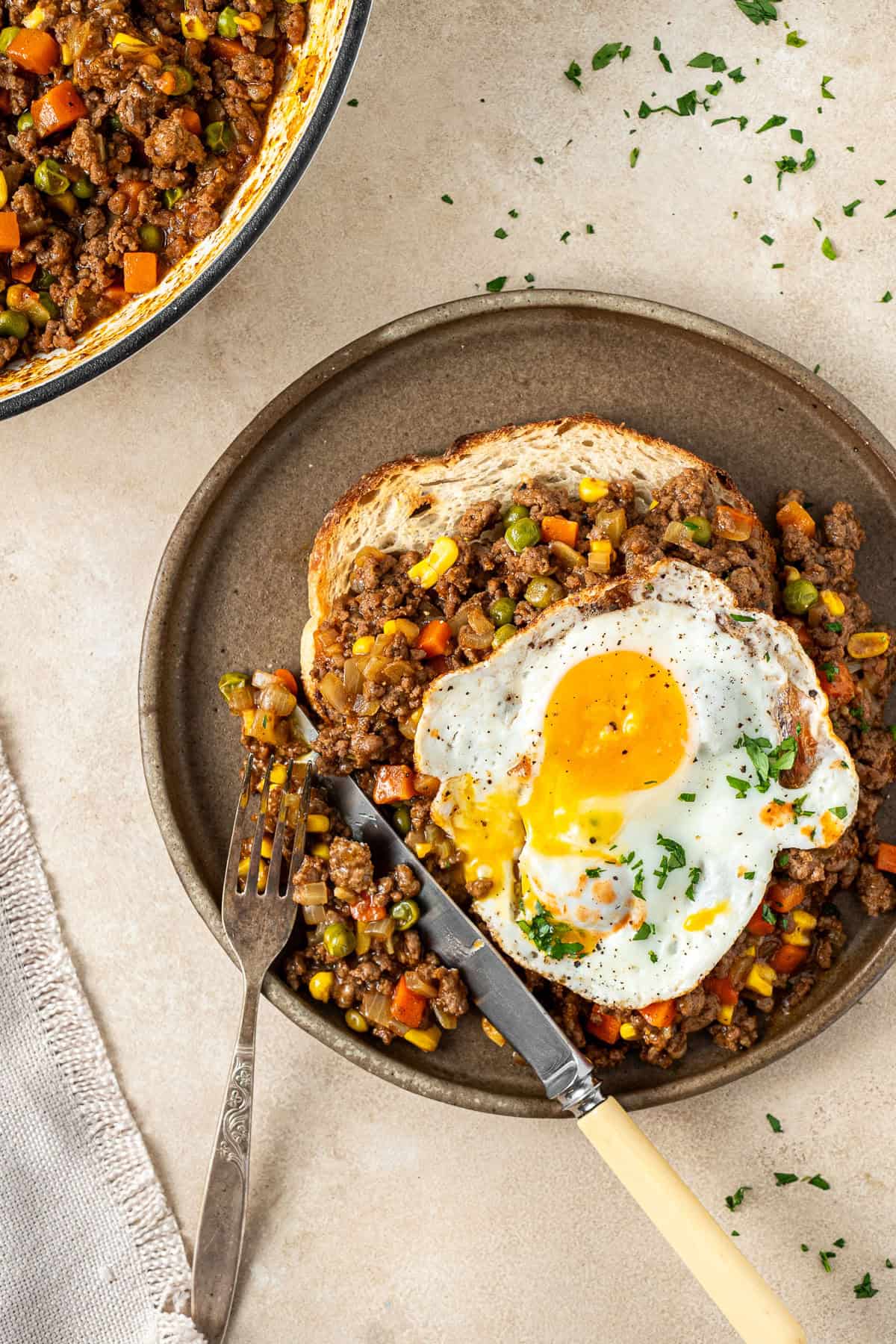 Savoury mince on a plate with a fried egg and a knife and fork.