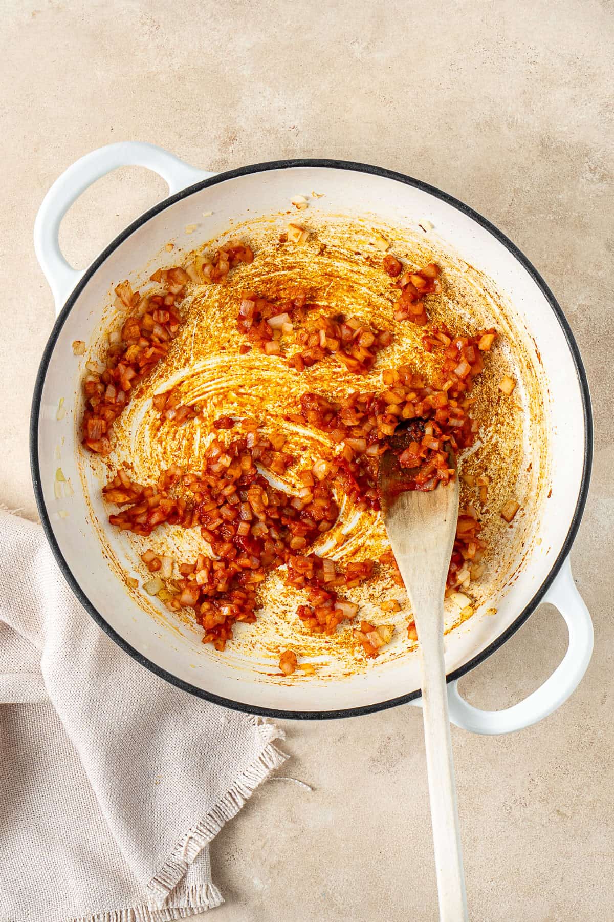 Cooking the tomato paste and curry powder with a wooden spoon.