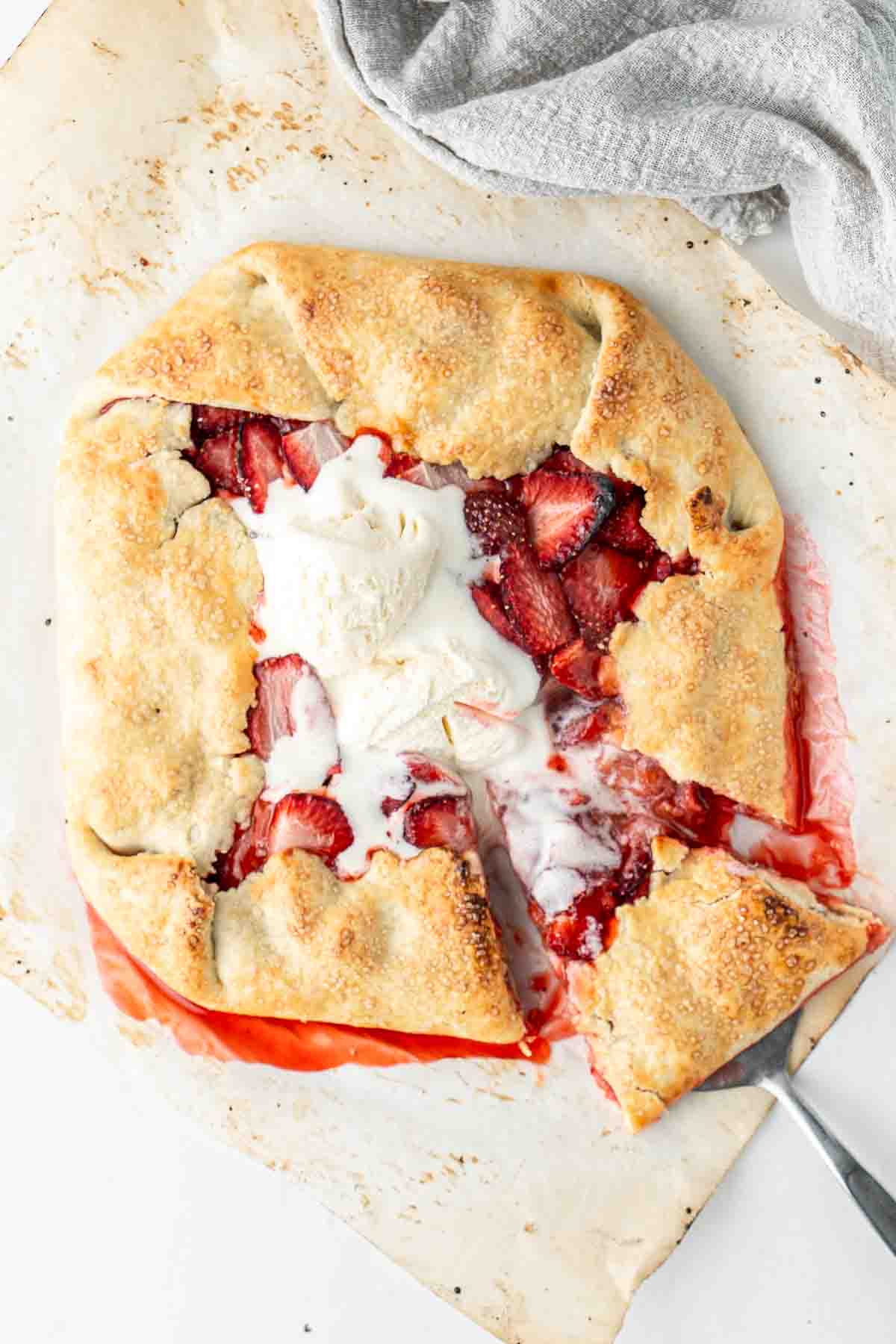 Strawberry galette with vanilla ice cream with a slice being served.
