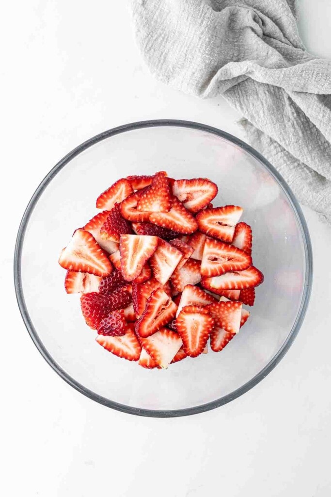 Sliced strawberries in a glass bowl. 