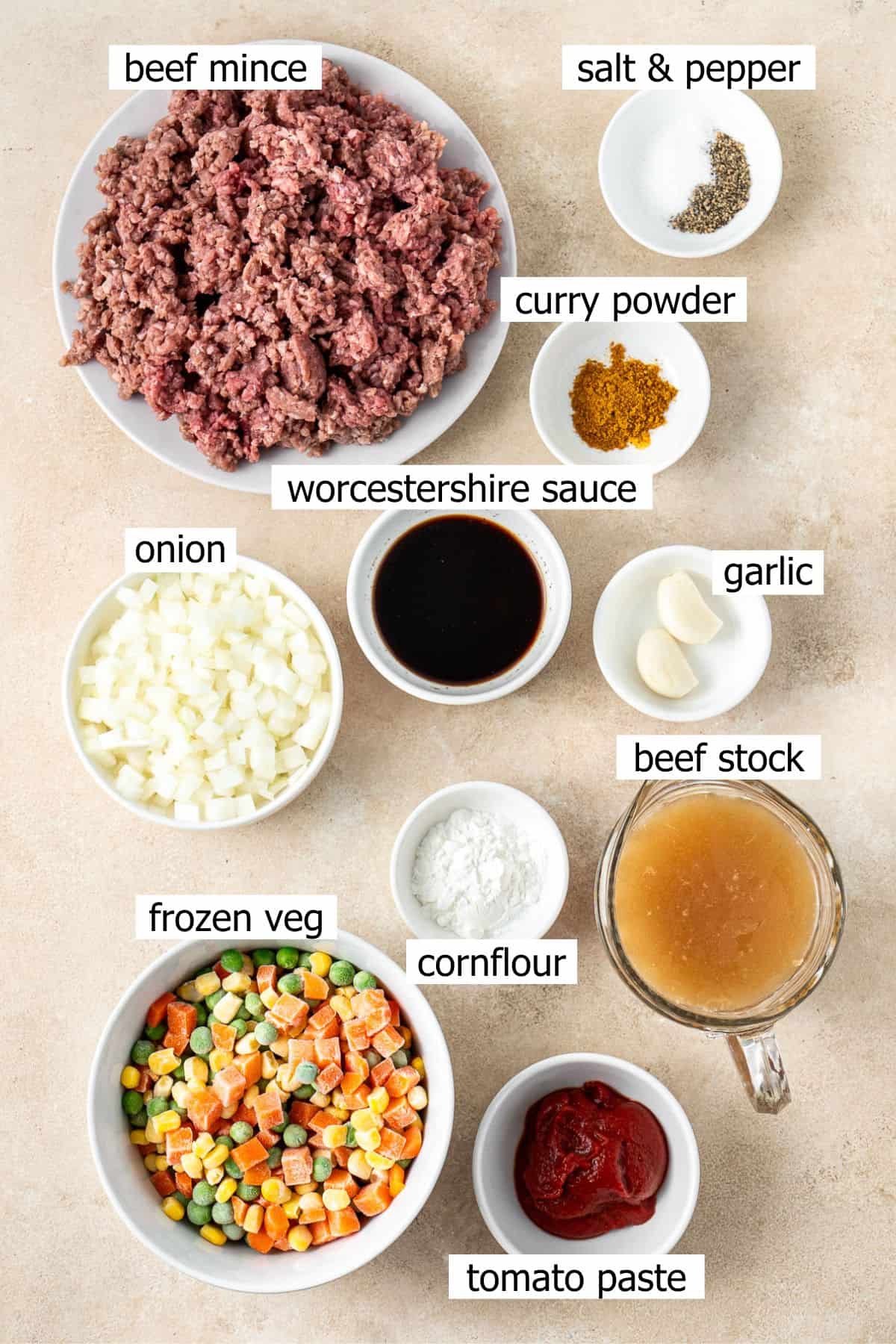 All ingredients needed to make savoury mince with curry powder laid out in small bowls.