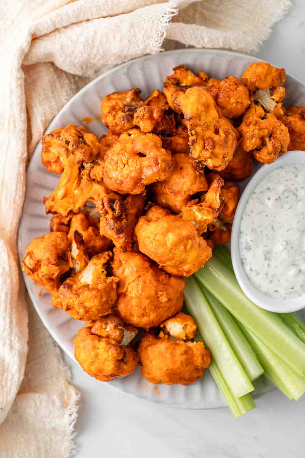 Buffalo cauliflower on a plate with celery and ranch dressing.