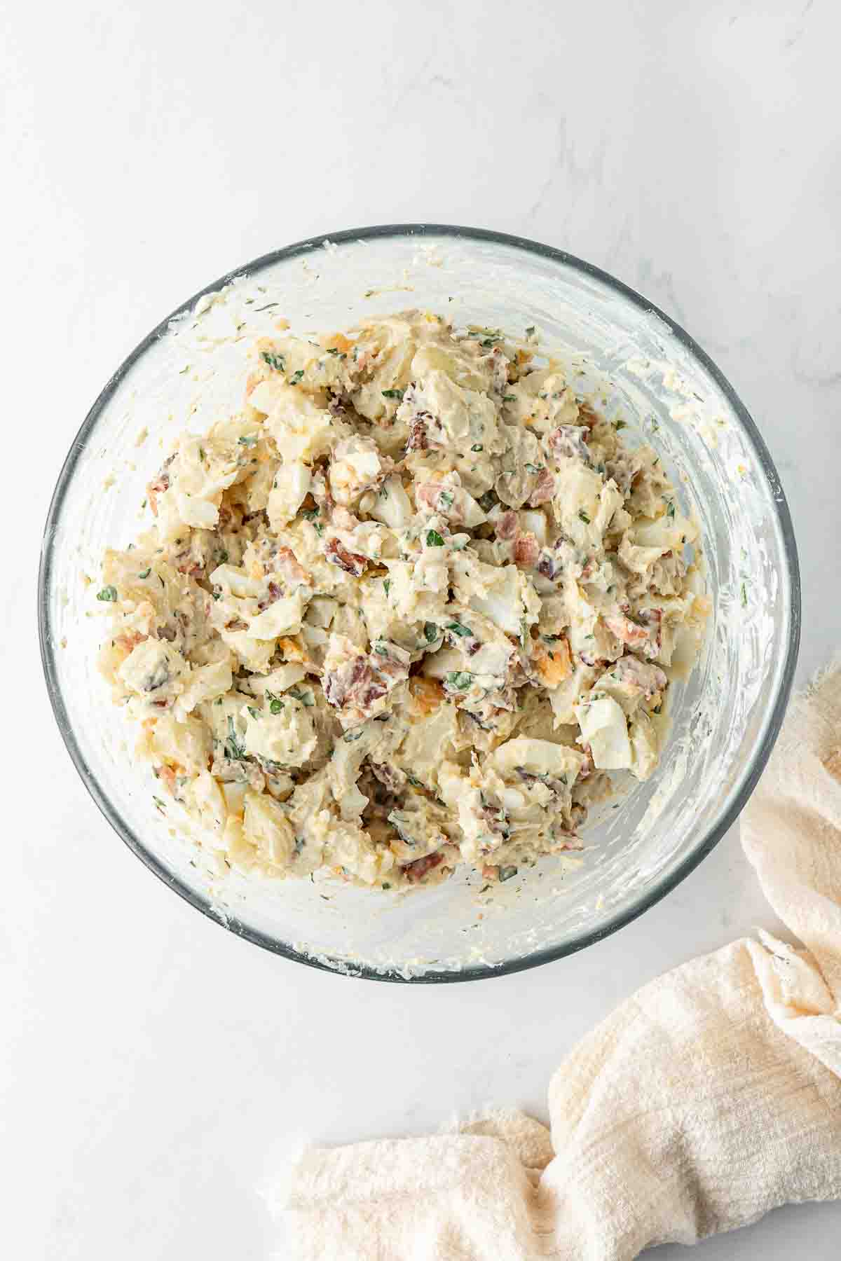Dairy free potato salad mixed up in a glass bowl, ready to serve.