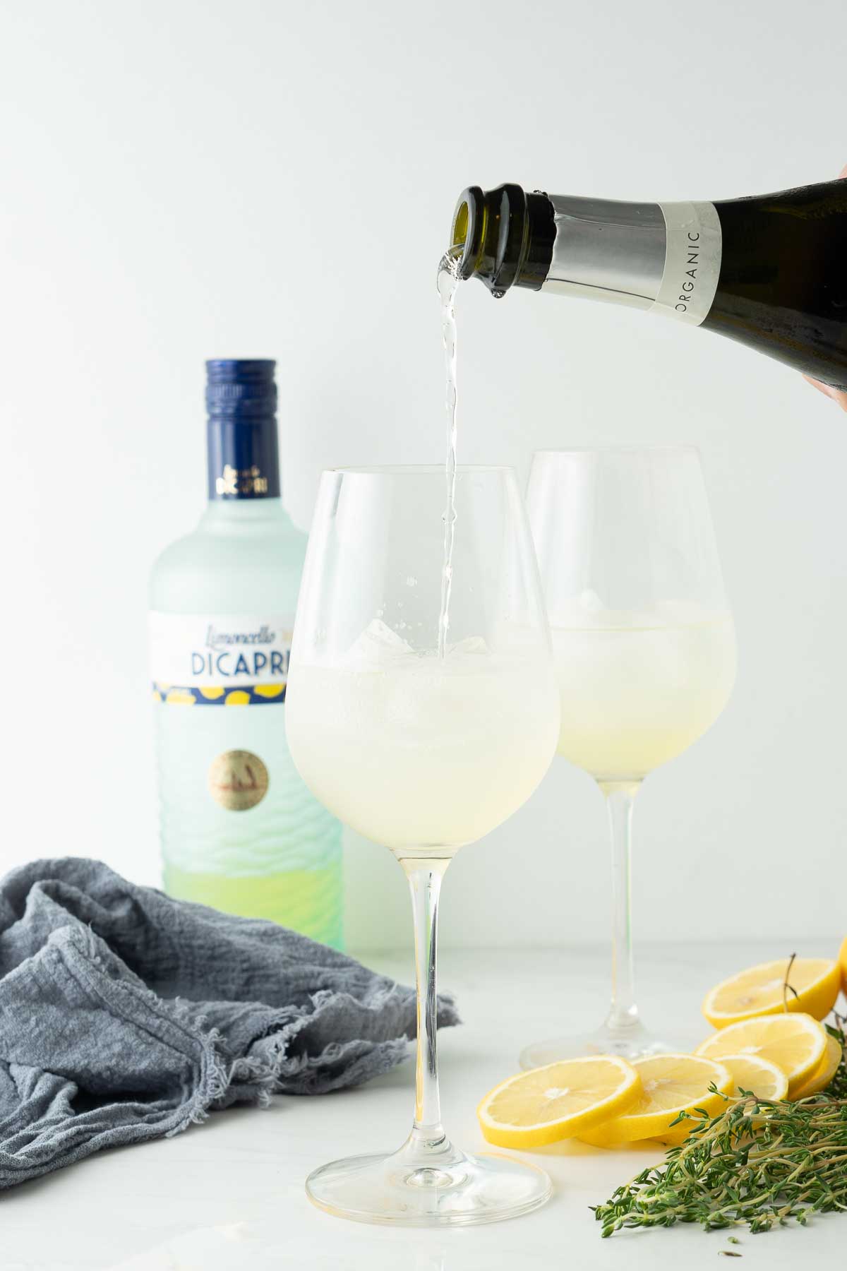 Making limoncello spritz by pouring in prosecco.