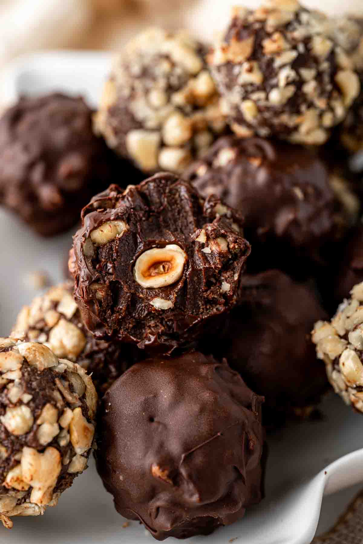 Close up of a vegan ferrero rocher with a bite taken showing the hazelnut in the centre.