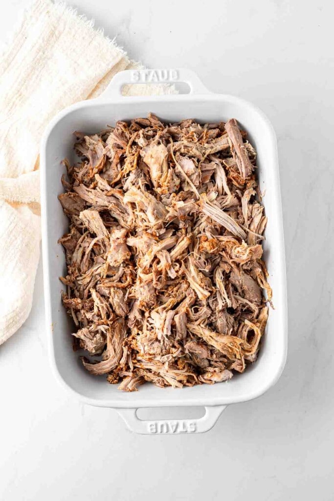 Pulled pork in a white casserole dish.