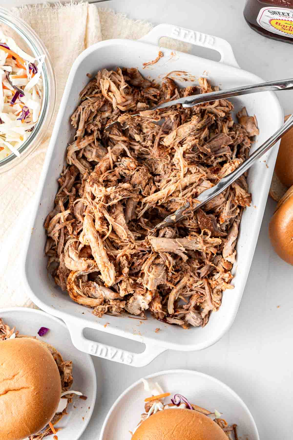 BBQ pulled pork in a disk with tongs for serving.
