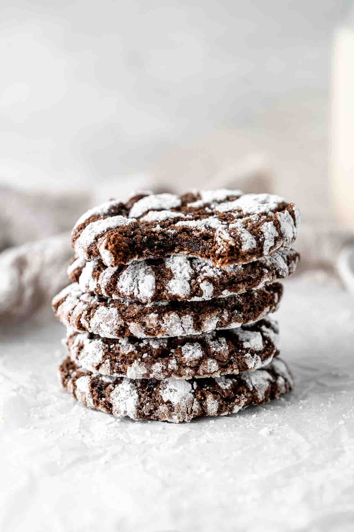 Stack of chocolate crinkle cookies with the top one having a bite taken. 