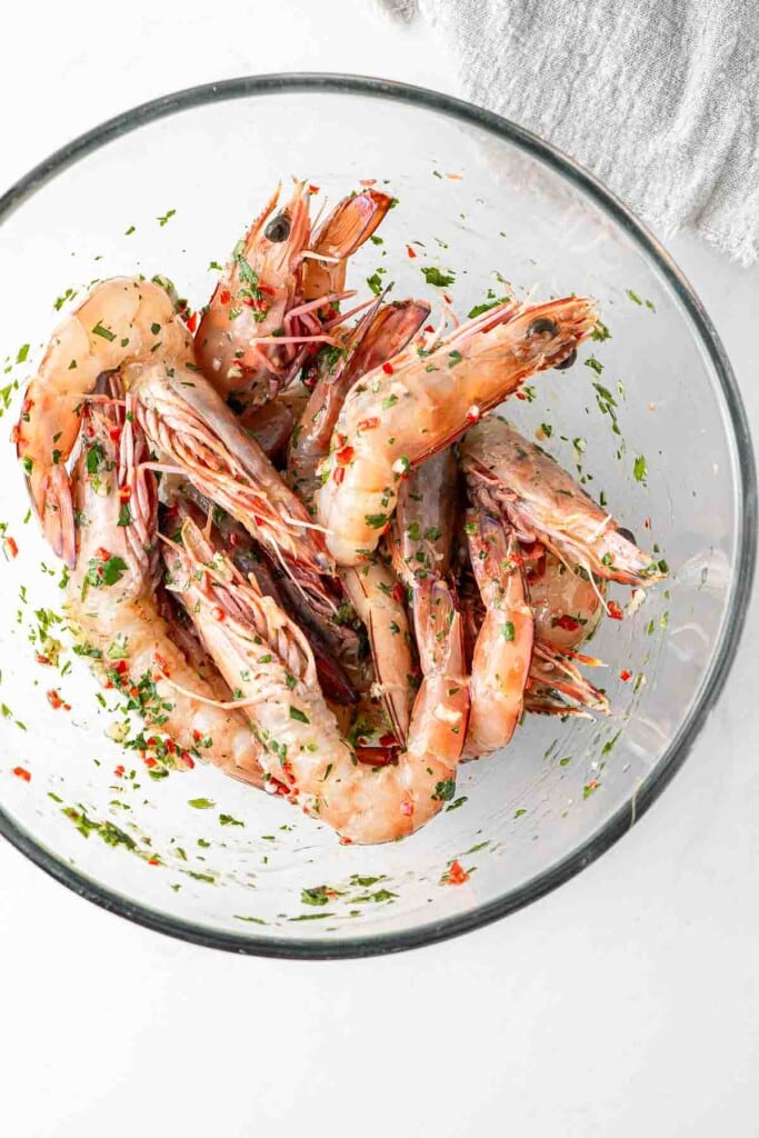 Prawns in a large glass bowl marinating. 