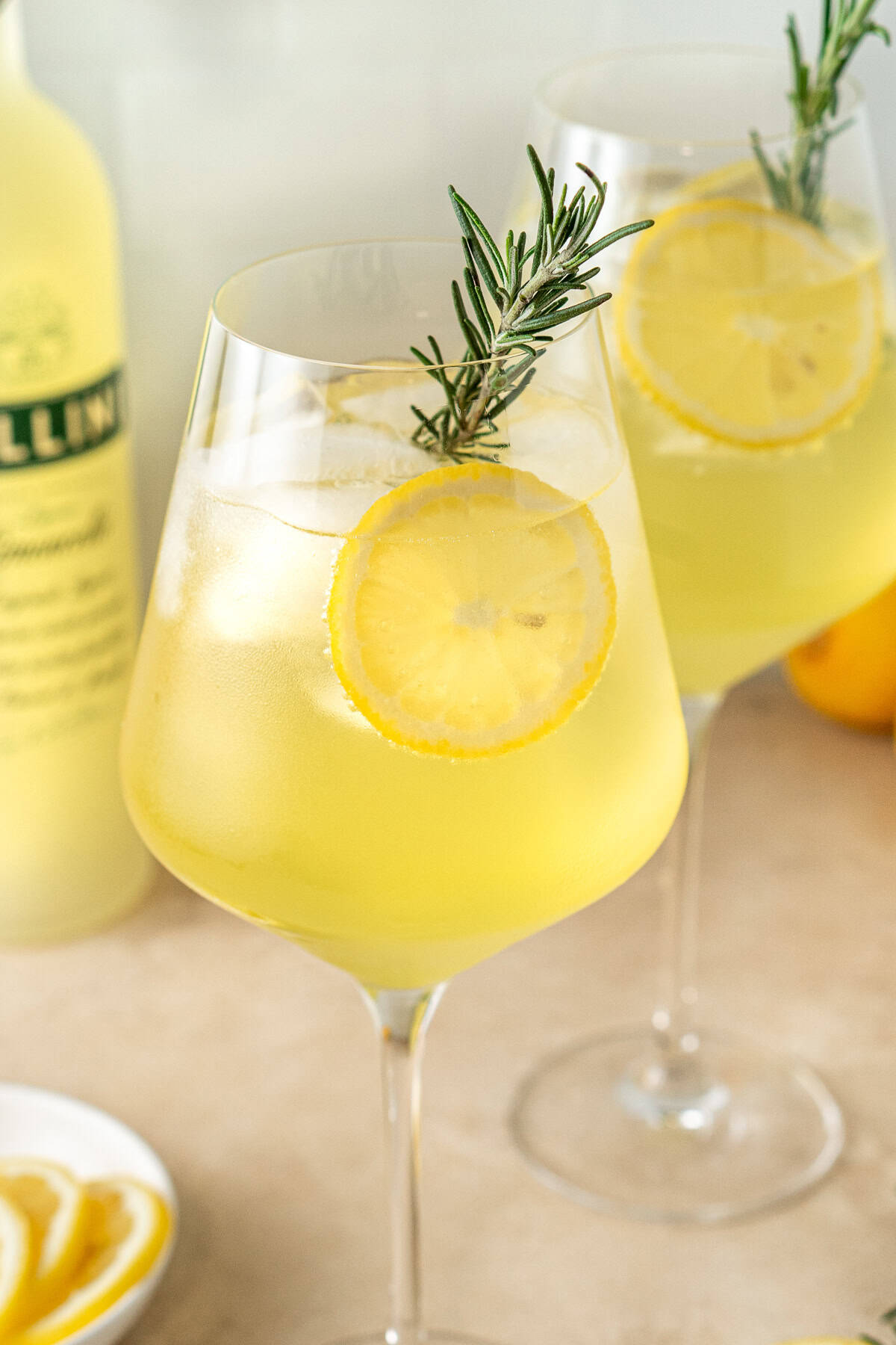 Close up of a limoncello spritz with rosemary and lemon slices.