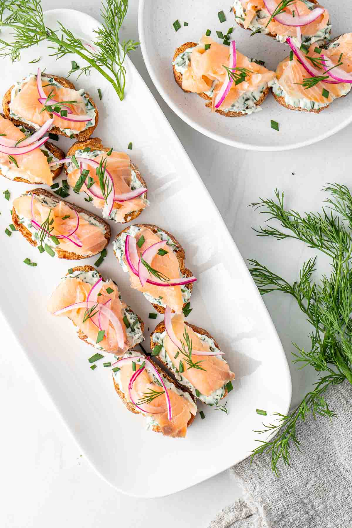 Smoked salmon crostini served on a long white platter from above.