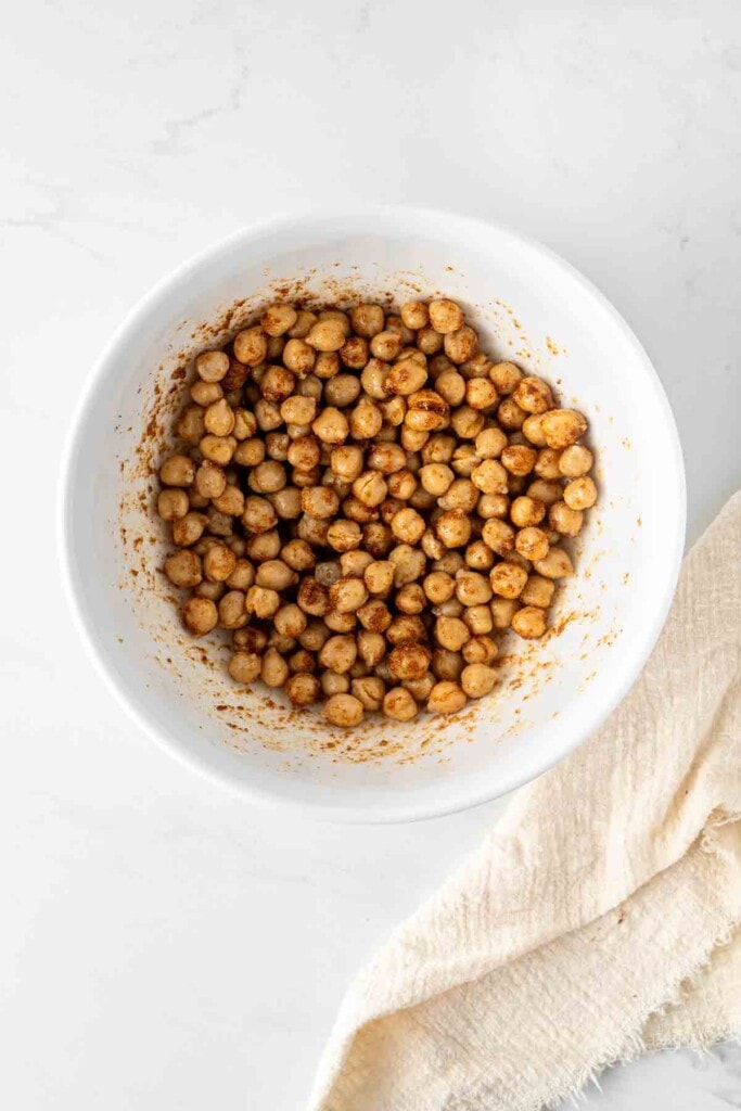 Chickpeas in a white bowl with oil and spices.