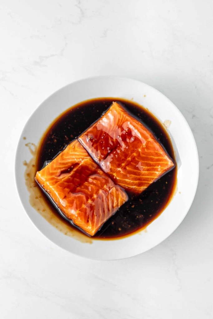 Salmon fillets marinating in teriyaki sauce.