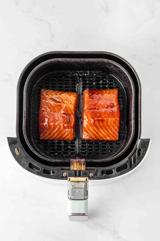 Marinated salmon fillets in the basket of the air fryer.