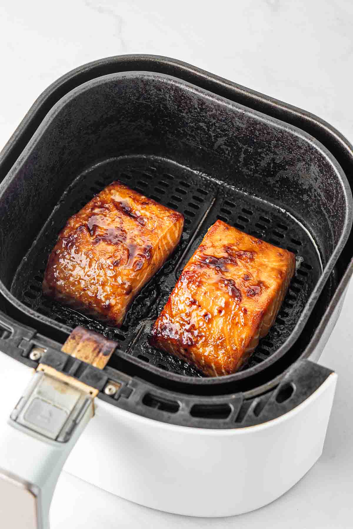 Cooked salmon fillets in the basket of the air fryer. 