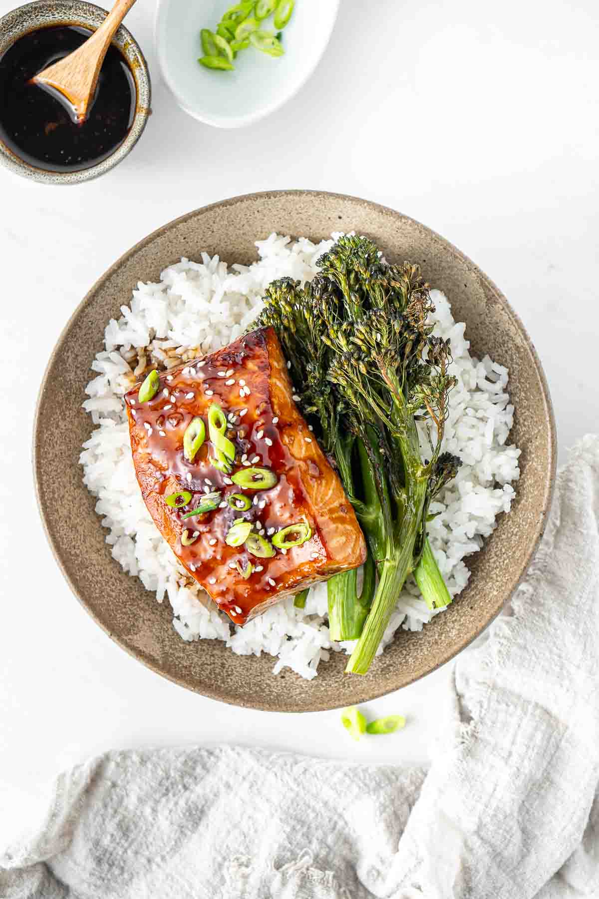 Teriyaki salmon fillet in a bowl with rice and roasted broccolini.