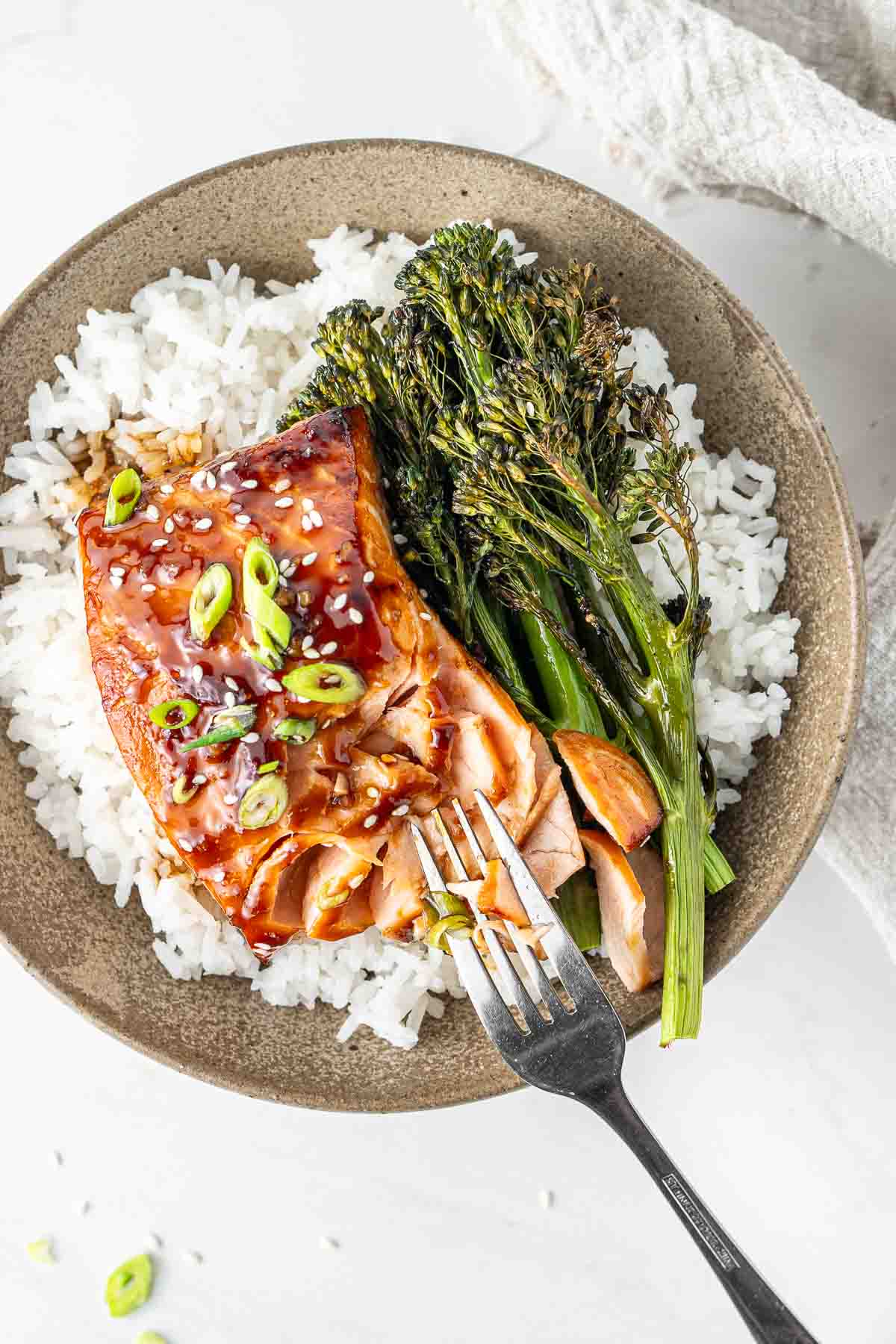 Air fryer teriyaki salmon in a bowl with roasted broccolini and white rice with a fork.