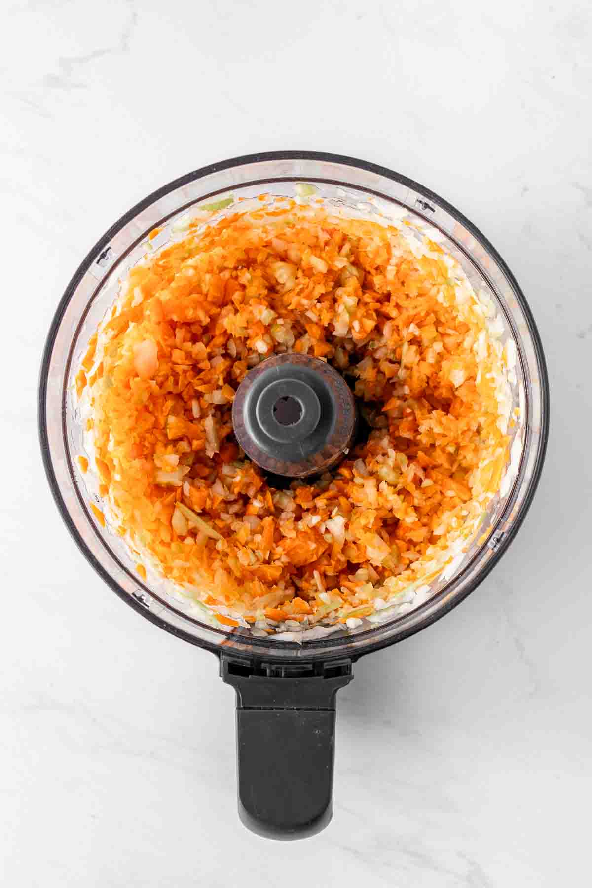 Chopped carrots, celery, and onion in food processor bowl.