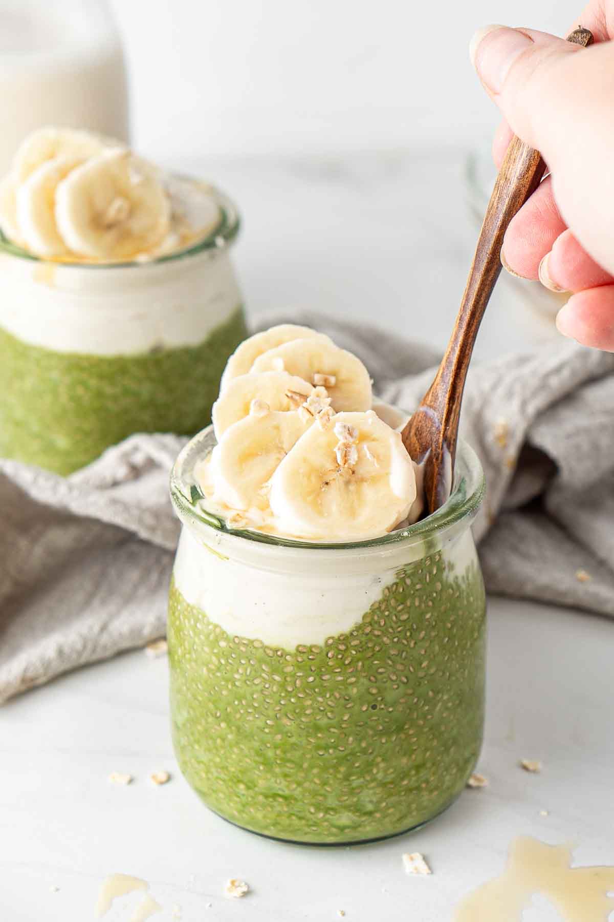 Matcha chia pudding with a wooden spoon taking a bite.