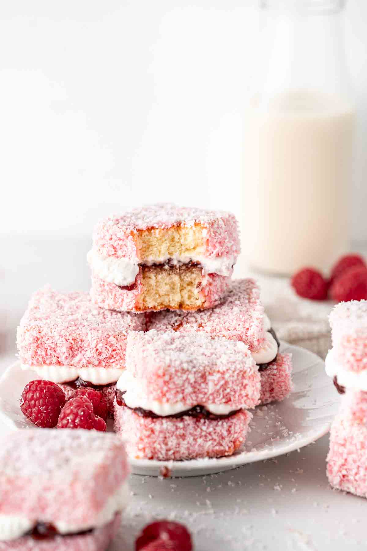 Raspberry lamingtons with jam and cream and a bite taken.