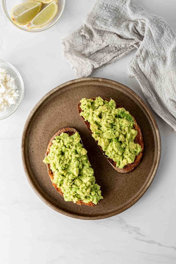 Smashed avocado on the toast on a plate.