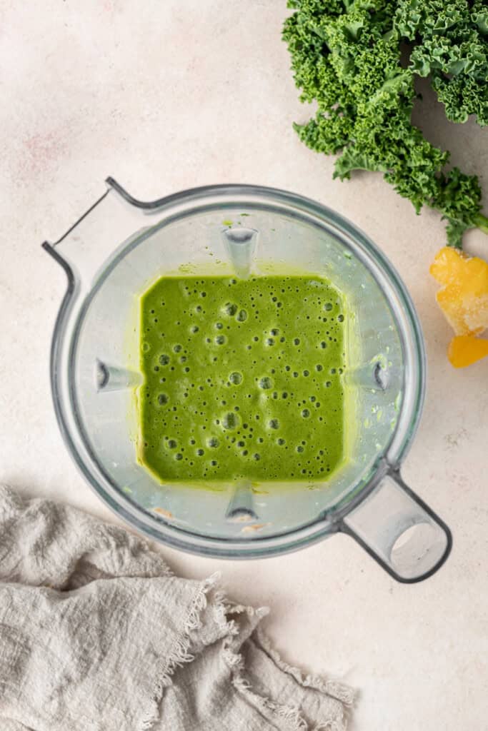 A bright green blended smoothie in a blender jug.