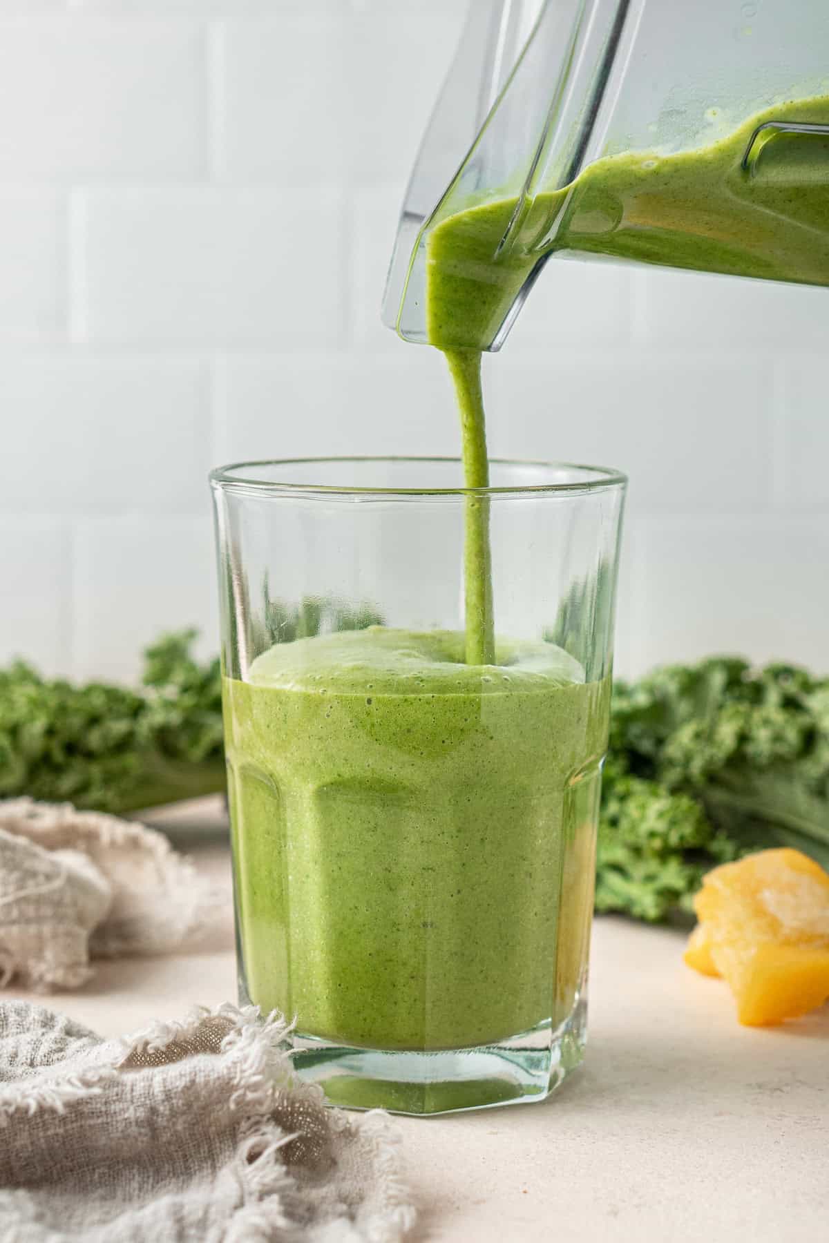 Pouring the green smoothie into the glass for serving.