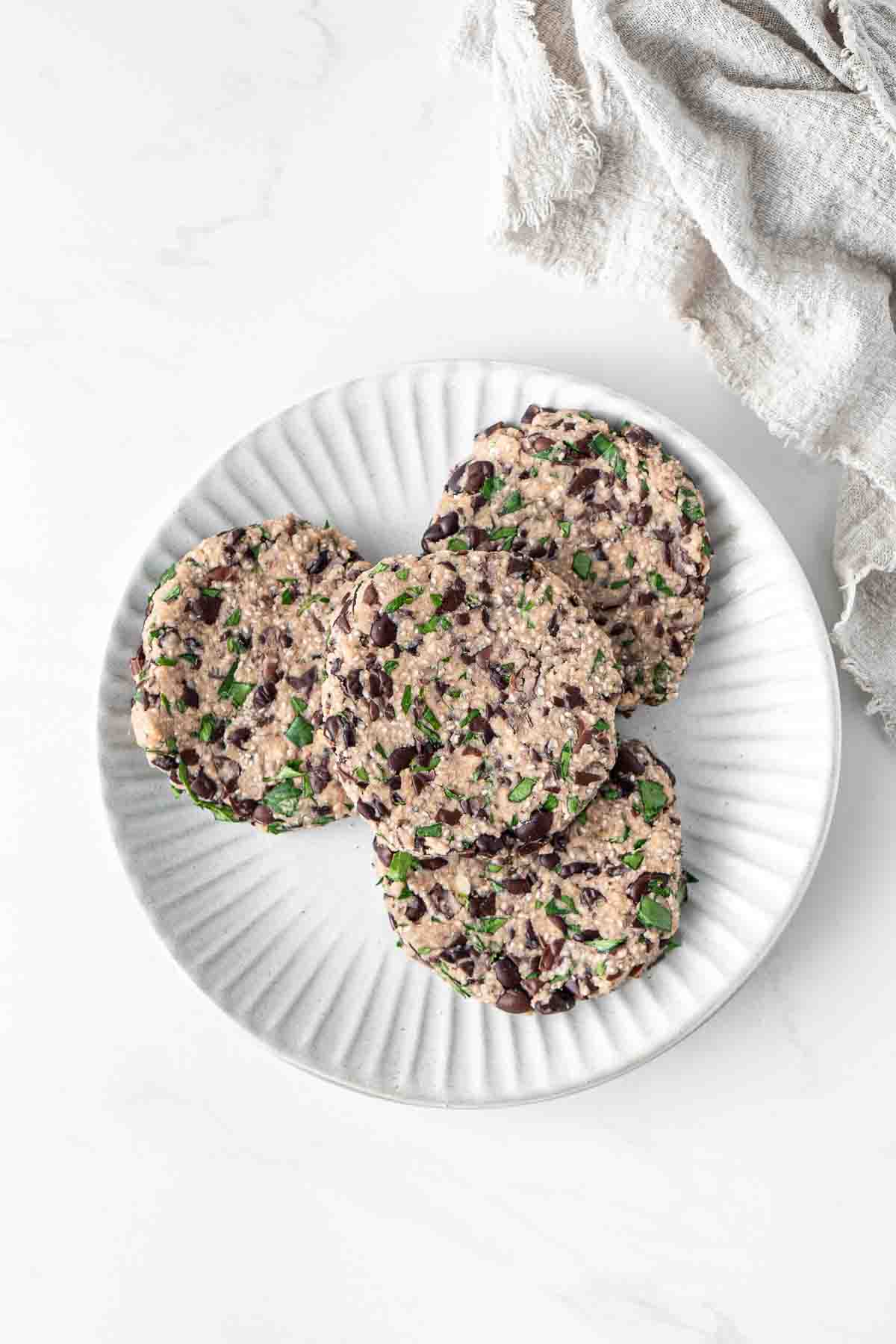 Uncooked black bean burger patties shaped into disks on a plate.