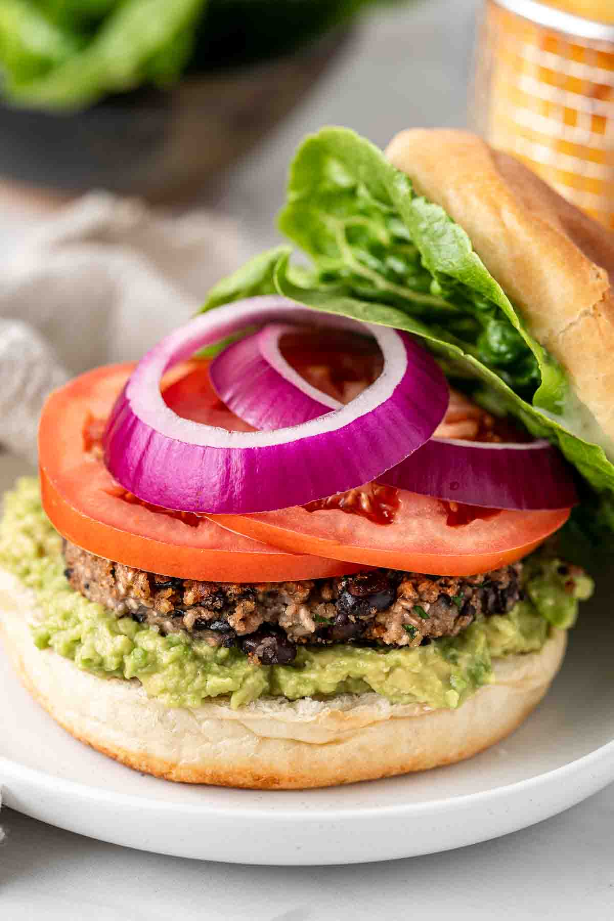 Sliced red onion and tomato on top of the vegan black bean burger.