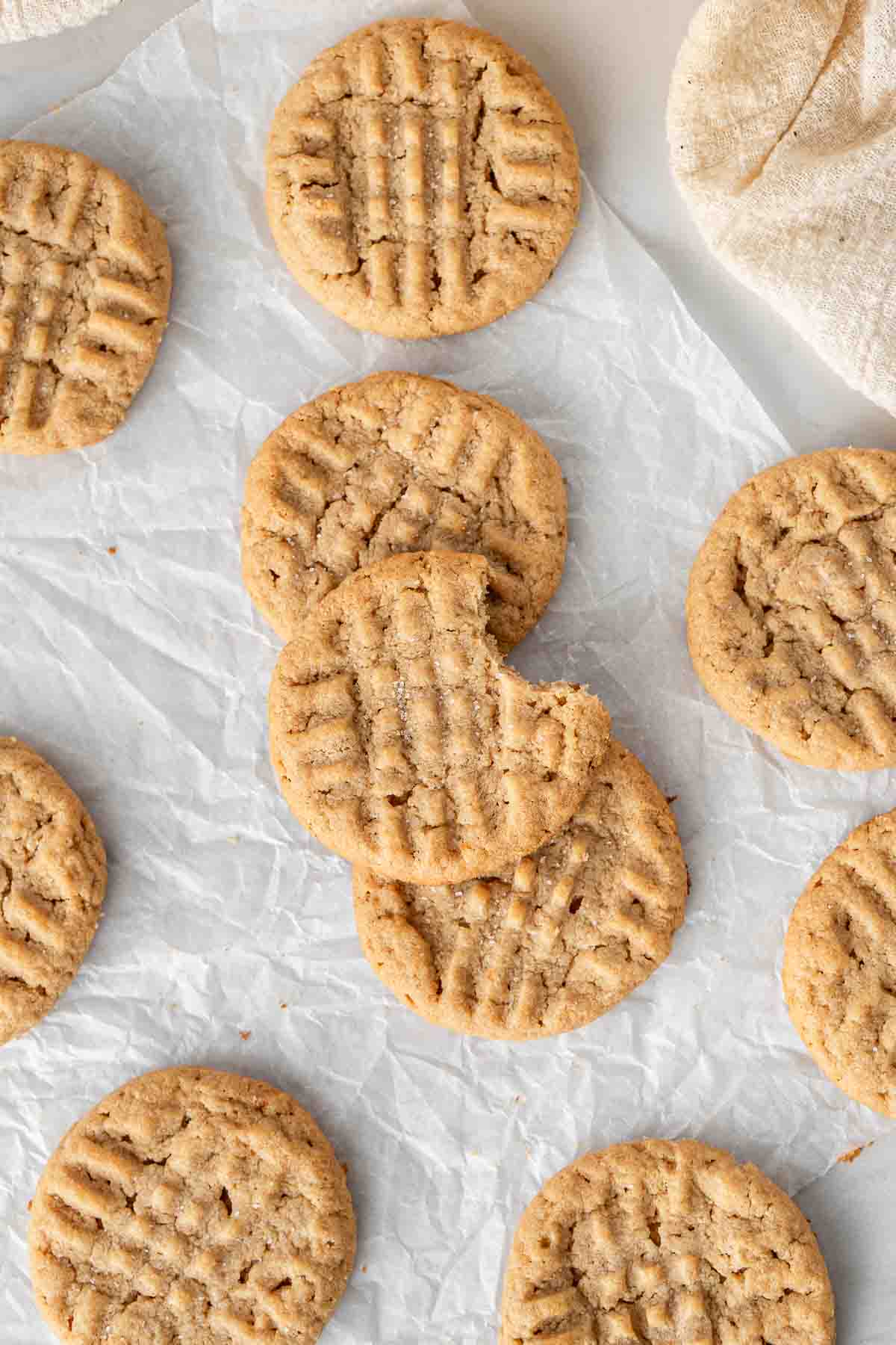 Vegan peanut butter cookies laid out from above, one with a bite taken.