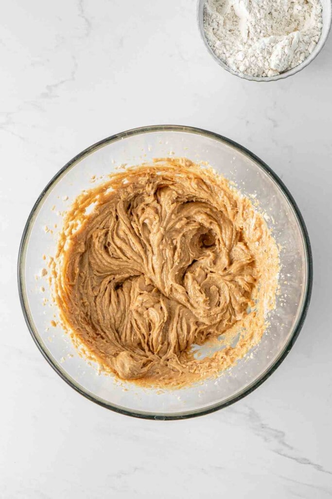 Creamy butter, peanut butter and sugars in a glass bowl.