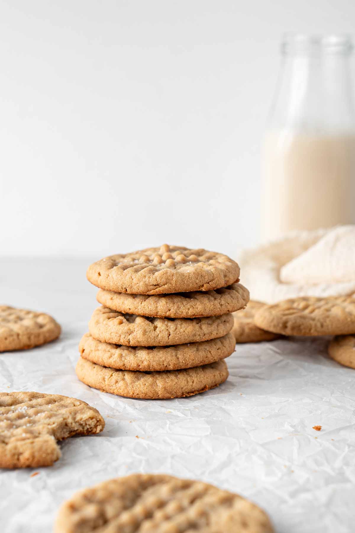 Stack of cookies with a glass of milk in the background.